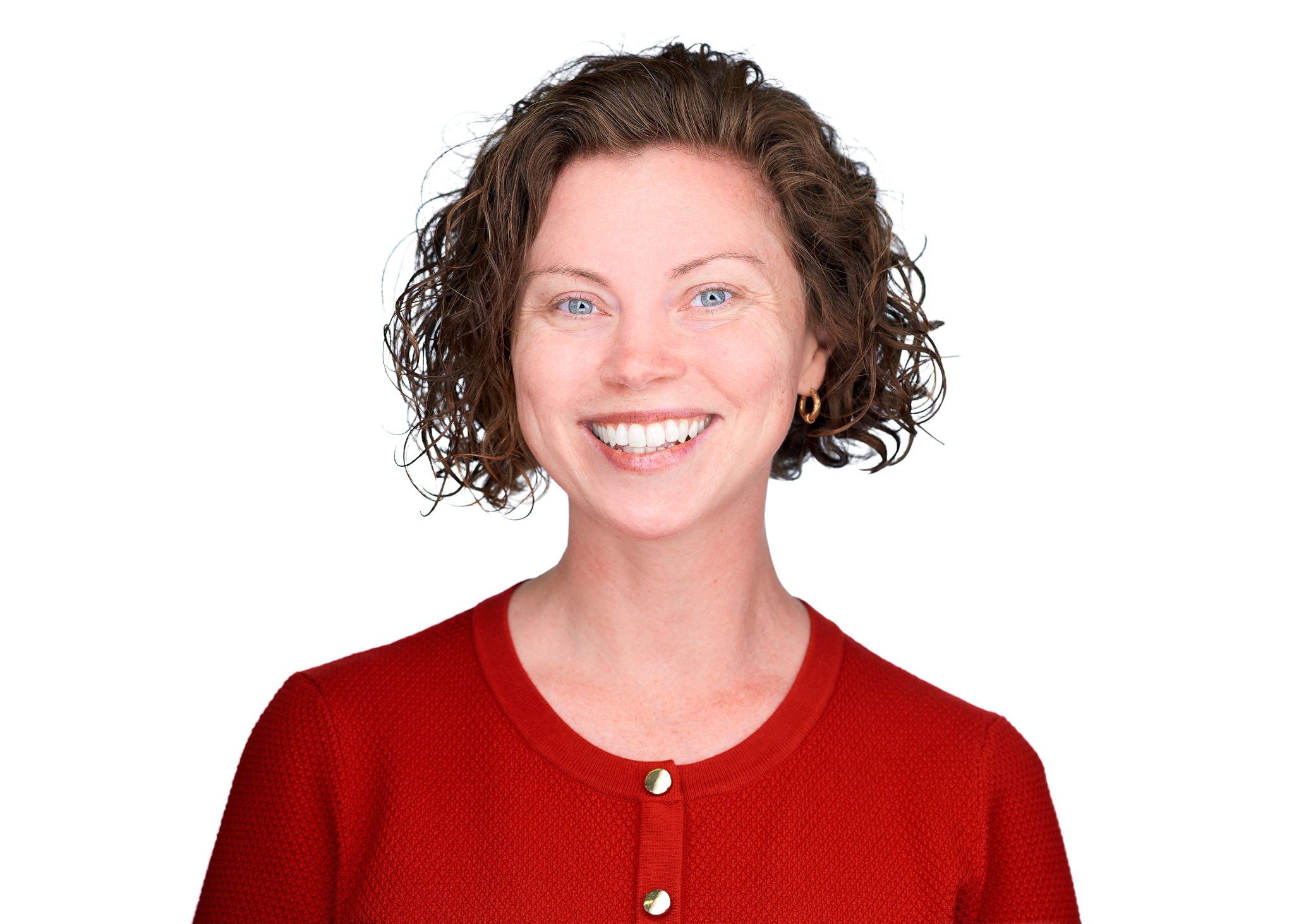 Headshot of a woman with short curly hair smiling, wearing a red top against a light background